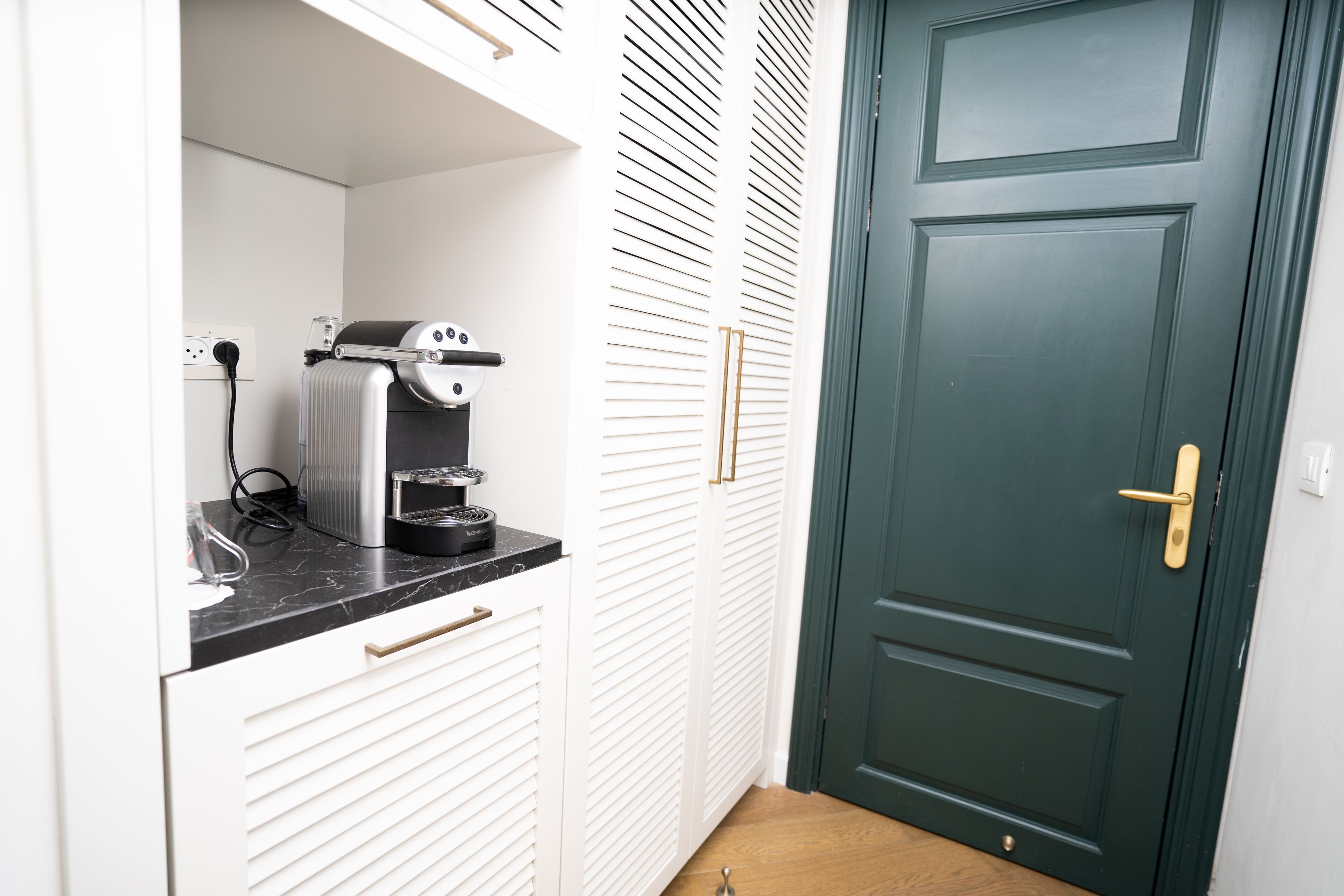 Una cocina compacta con cafetera, una encimera y una puerta verde.