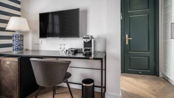 Une chambre moderne équipée d’un bureau, d’une chaise, d’une télévision, d’une machine à café et d’une poubelle.