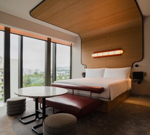 Una camera d'albergo moderna con un letto grande, un tavolo rotondo, una panca e vista sulla città.
