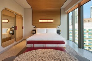 A modern hotel room with a large bed, a round seating area, a wooden ceiling, and a view of buildings through large windows. - Orange Grove Serviced Residences (Singapore)