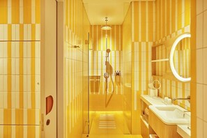 Un bagno con piastrelle gialle e bianche a strisce, una doccia, un lavandino e uno specchio.
