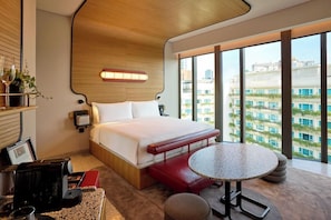 A modern hotel room with a large bed, a small round table, and a view of the city through large windows. - Orange Grove Serviced Residences (Singapore)