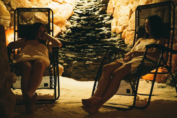 Two individuals seated in chairs in a room with a stone wall and a small heater. - Hotel Horní Dvůr (Nové Mesto na Morave)