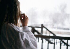 A person in a white robe standing by a railing, overlooking a snowy landscape. - Hotel Horní Dvůr (Nové Mesto na Morave)