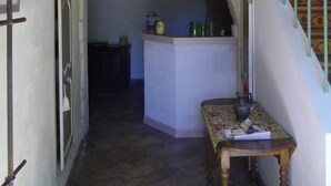Un couloir étroit, surmonté d’une arche en pierre, mène à une cuisine.