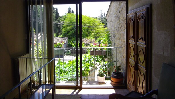 Un balcon donnant sur un jardin et un immeuble.