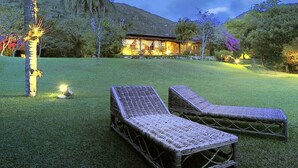 Un espacio exterior bien iluminado con dos sillones de mimbre y un edificio al fondo.