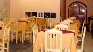 Una habitación con varias mesas y sillas de madera, dispuestas en filas.