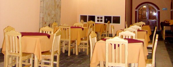 Una habitación con varias mesas y sillas de madera, dispuestas en filas.