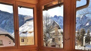 A wooden interior with a dining table and chairs, large windows with a snowy mountain view. - Der Ulmenhof (Gosau)