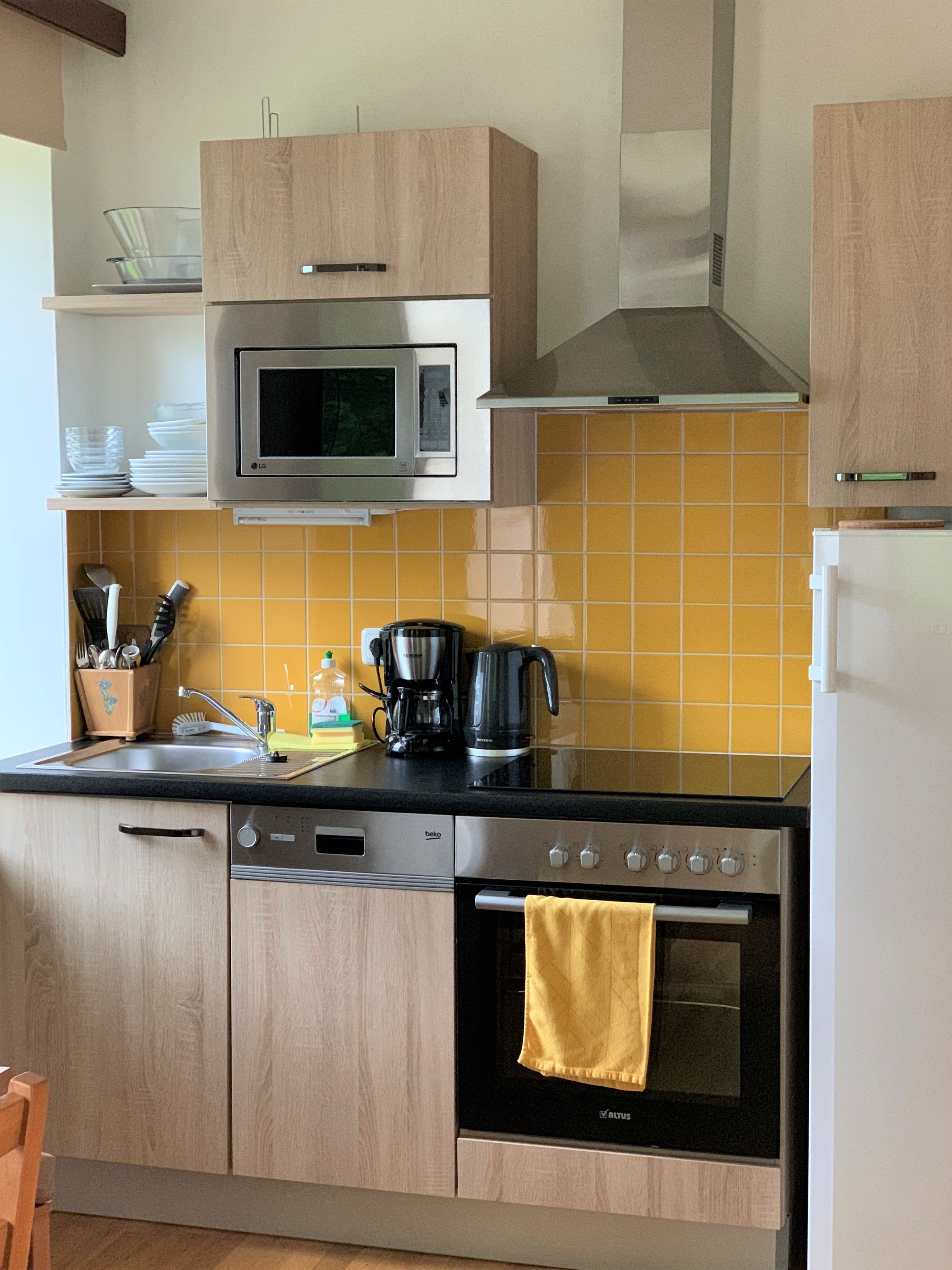 Eine moderne Küche mit Holzausstattung, einer Mikrowelle, einer Kaffeemaschine und einem Backofen.