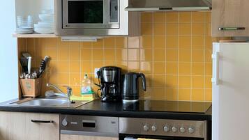 Eine moderne Küche mit Holzausstattung, einer Mikrowelle, einer Kaffeemaschine und einem Backofen.