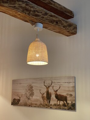 A rustic ceiling beam, a woven pendant light, and a wildlife-themed painting on a wall. - COOEE alpin Apartments Gosau (Gosau)
