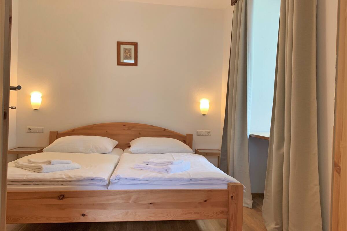 A double bed with wooden headboard and footboard, two bedside tables, and two wall-mounted lights.