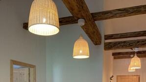 A cozy room with a wooden dining table, grey upholstered sofa, and two hanging wicker lamps. - Der Ulmenhof (Gosau)