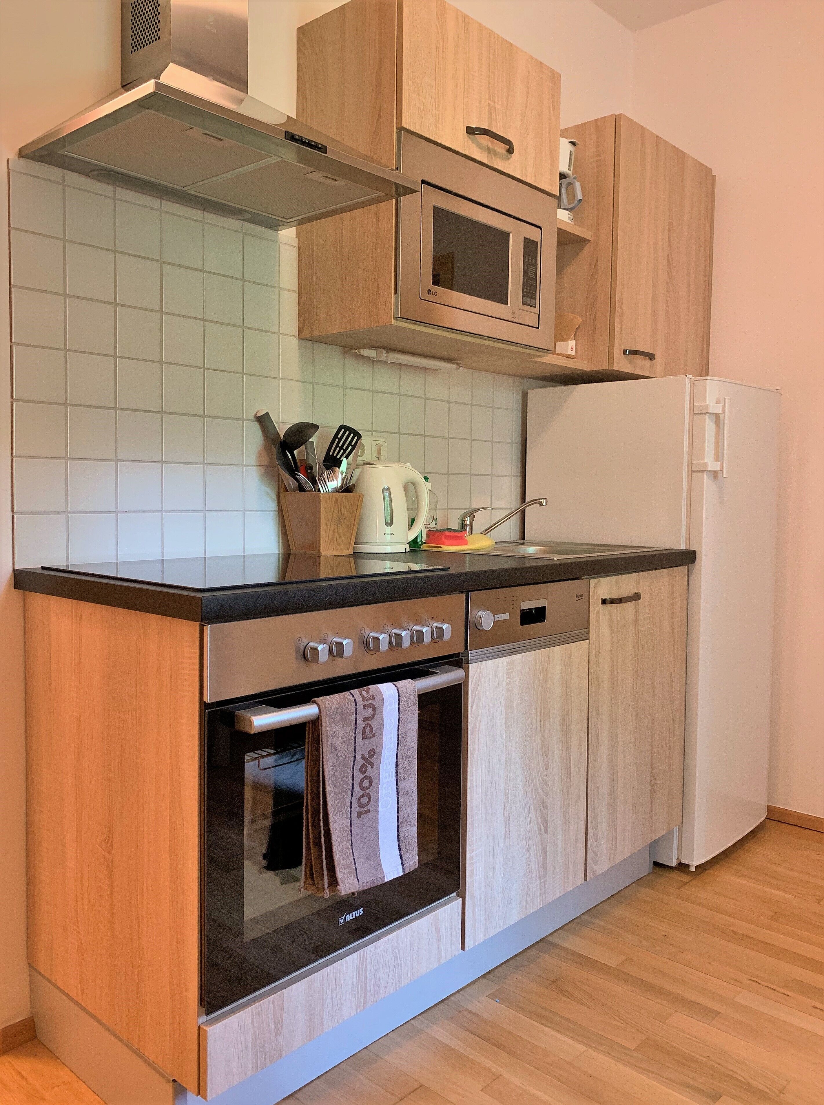 Cozinha com armários de madeira, fogão de aço inoxidável, micro-ondas e forno embutido.