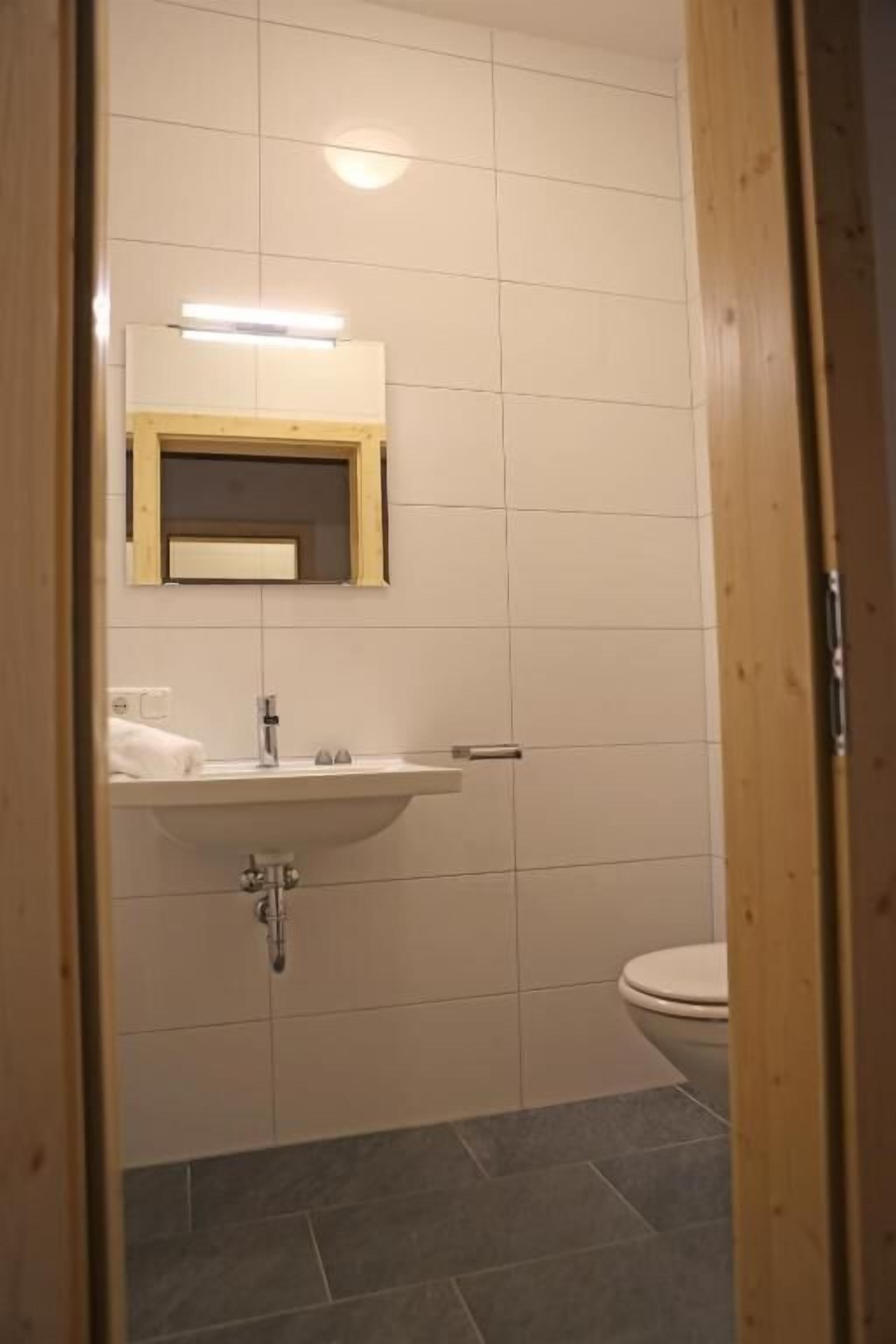 A bathroom with a white sink, mirror, and toilet.
