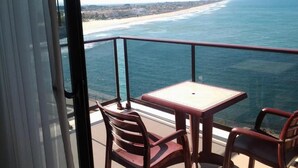 Un balcón con mesa y sillas con vistas a una playa y al océano.