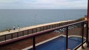 A pool area with a view of the sea, a walkway, and a few people walking. - Aparthotel El Faro (Cullera)
