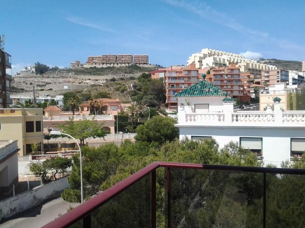 Zona residencial con edificios de varios pisos, incluyendo un edificio blanco con techo verde y uno rojo con balcones.