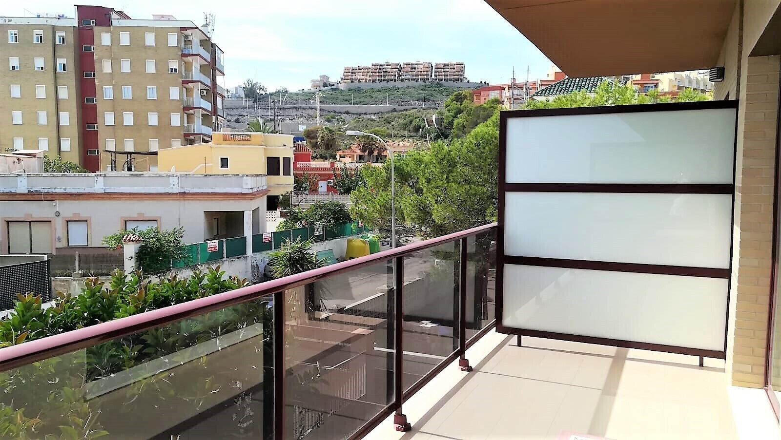 Ein Balkon mit Blick auf eine Stadtlandschaft, einschließlich Gebäude und einer Hügelkette in der Ferne.