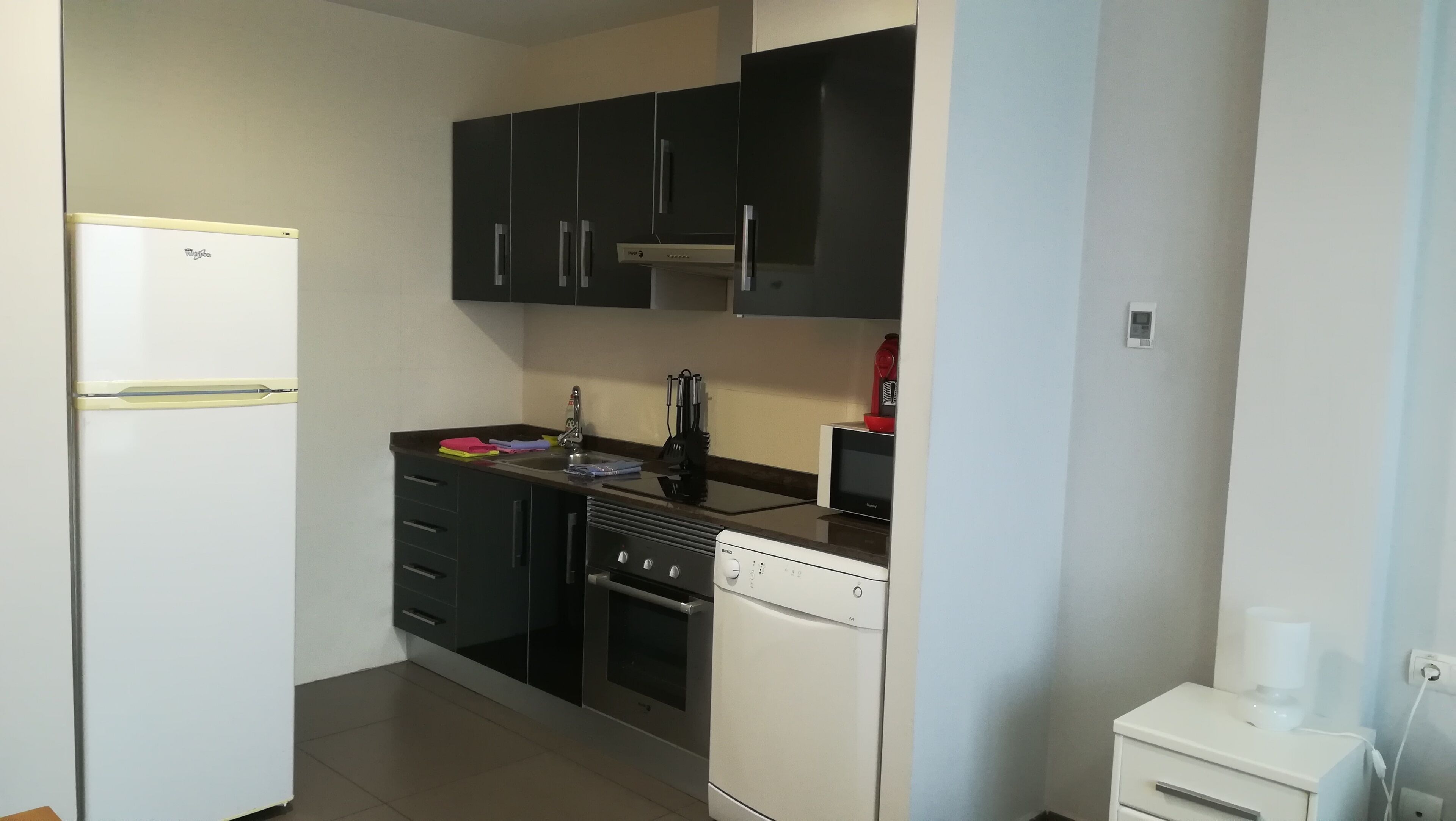 A compact kitchen with a refrigerator, stove, oven, and dishwasher.