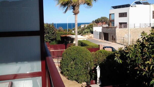 Un balcón con vistas a una palmera, un edificio moderno y un cielo despejado.