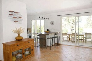 Una cocina con comedor, lavadora y un amplio ventanal.