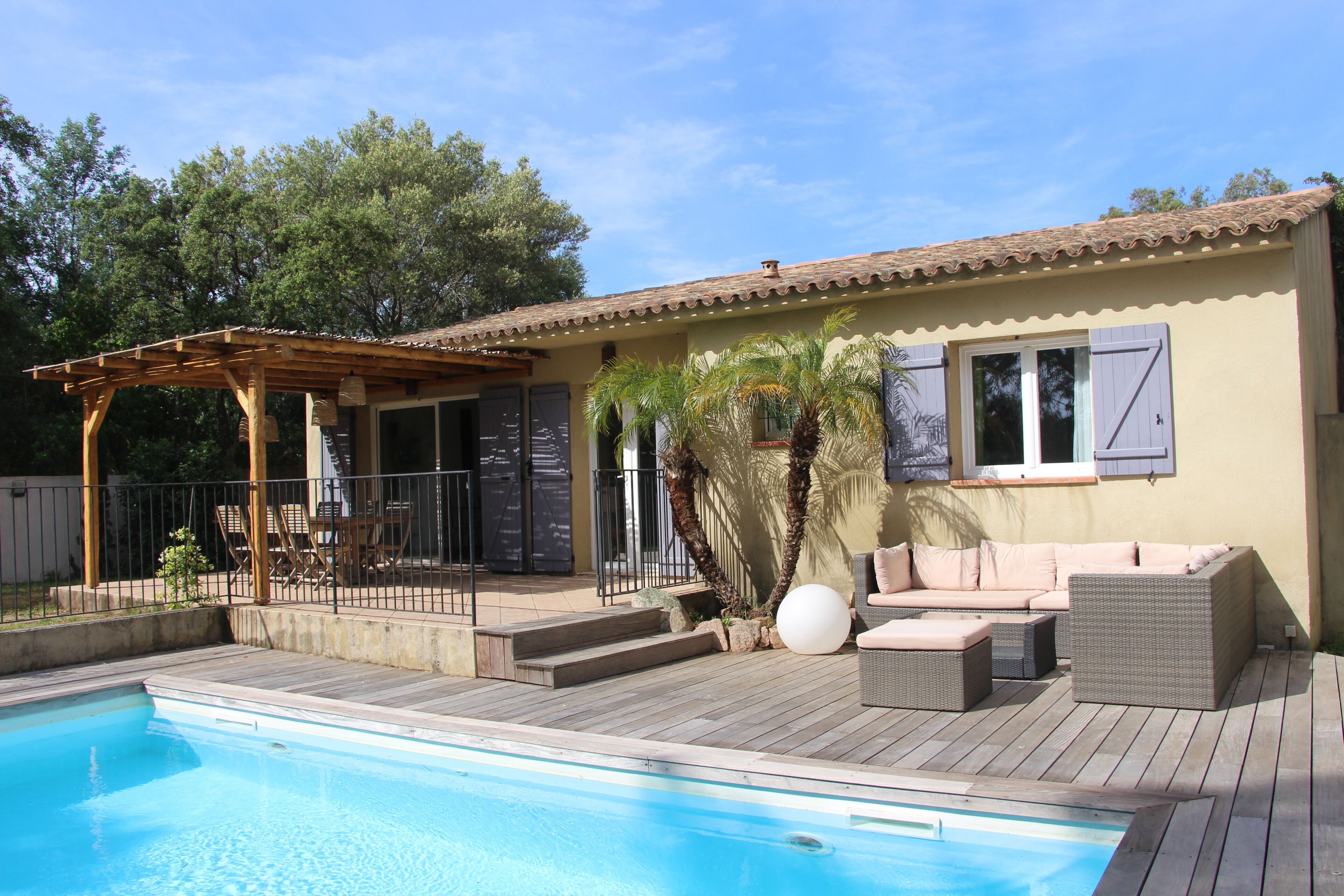 Zona junto a la piscina con una pérgola, mobiliario exterior y una piscina.