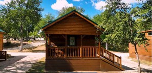 Situated among the trees, this cabin-style building features a cozy porch with a bench and railing.