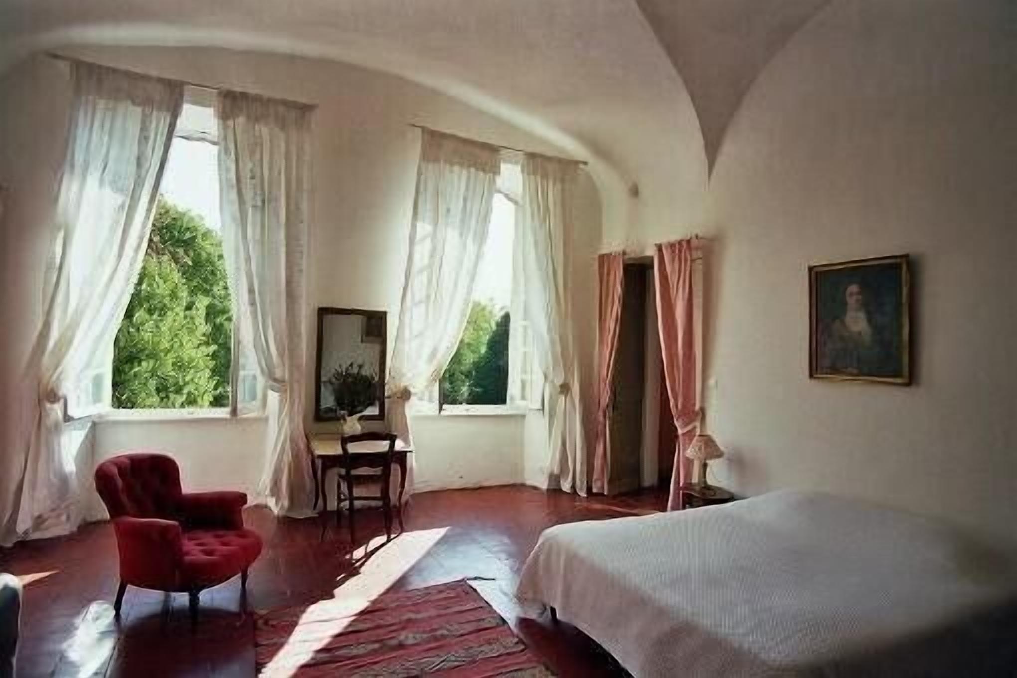 Ein Schlafzimmer mit einem Bett, einem Sessel, einem Schreibtisch und einem Gemälde.