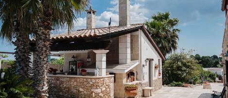 A stone building with a tiled roof, a stone bar area, and a bench.