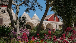 A building with a stone facade, arched windows, and a red roof. - Trulli D'Autore (Martina Franca)