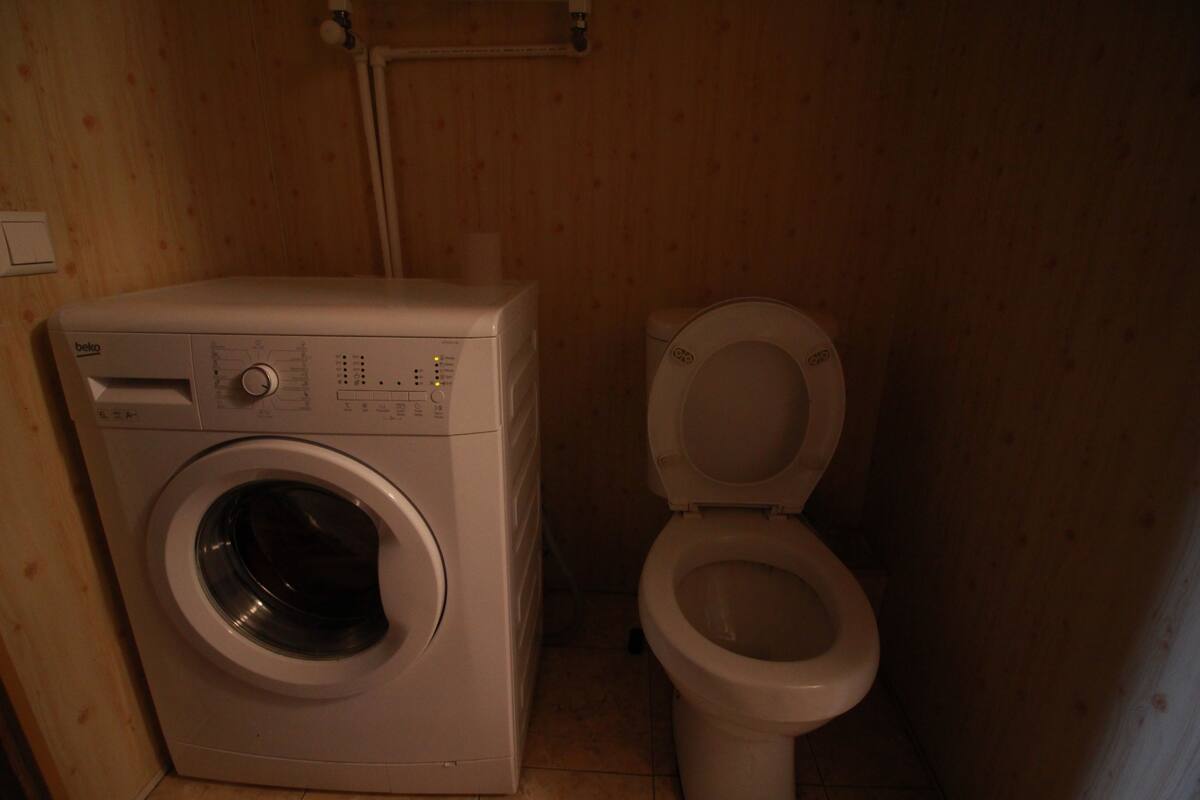 Une petite salle de bain équipée d’un lave-linge et de toilettes.