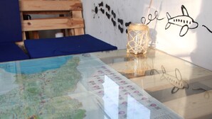 Une carte posée sur une table en verre, avec un banc en bois et un mur orné d’un dessin de requin.