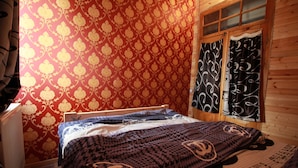 Une pièce avec un papier peint à motifs, un lit recouvert d’une courtepointe à motifs et une fenêtre avec des rideaux.
