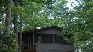 Eine zweistöckige Holzhütte, umgeben von dichtem Wald.
