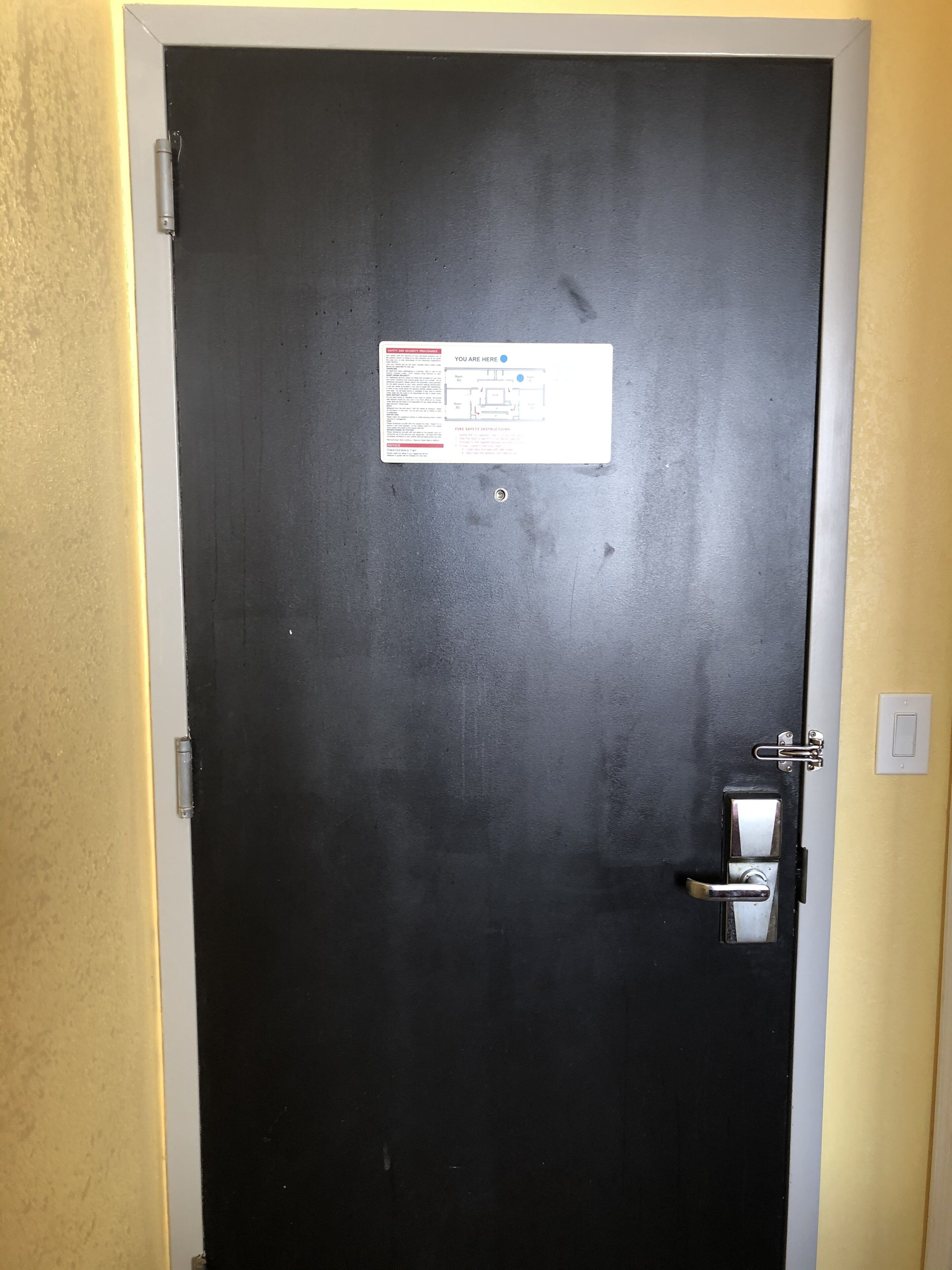 A closed black door with a fire safety instruction sign and a keycard reader.
