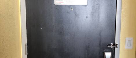 A closed black door with a fire safety instruction sign and a keycard reader.