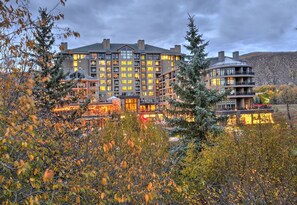 Ein mehrstöckiges Hotel mit Innenhof, umgeben von Bäumen und einer Berglandschaft.