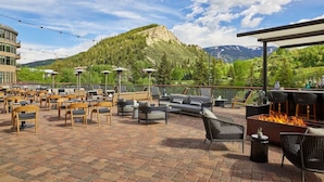 An outdoor patio area with multiple seating options, a fire pit, and a view of a mountain. - Charlie's Slopeside: Gondola Access, Private Patio, Resort Amenities, BC Views, Ski Valet + Pool (Avon)