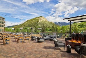 An outdoor patio area with multiple seating options, a fire pit, and a view of a mountain.