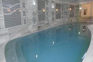 Swimmers can enjoy a refreshing dip in the rectangular pool surrounded by a geometric patterned wall.