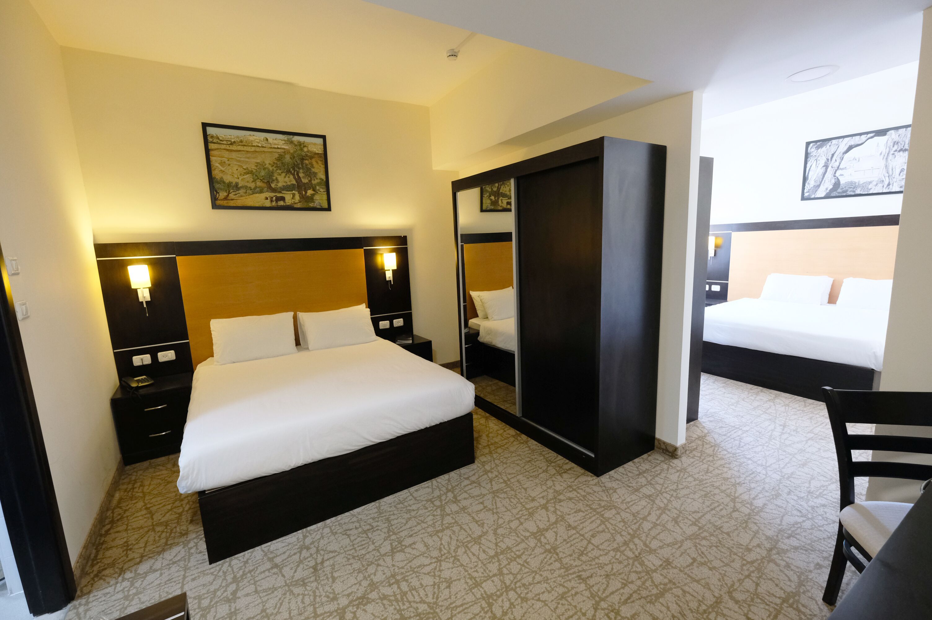 A hotel room with a large bed, a wardrobe, a desk, and a chair.