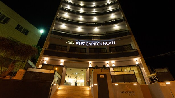 New Capitol Hotels facade om natten, med et moderne design, flere balkoner og en markant indgang med trapper op til døren.