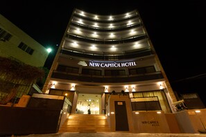 The exterior of the New Capitol Hotel at night, featuring a modern design with multiple balconies and a prominent entrance with steps leading up to the door. - New Capitol Hotel - Jerusalem (Jerusalem)
