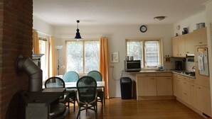 A compact kitchen with a dining area, a TV, and a clock on the wall.