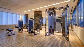 A gym with various exercise machines, wooden flooring, and large windows with blinds. - Nido x Quartier Dorrego (Buenos Aires)