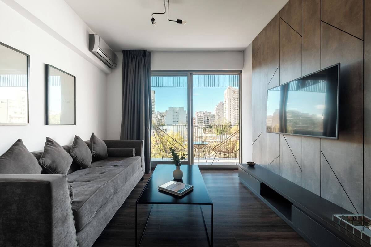 A modern living room with a sofa, coffee table, and a flat-screen TV mounted on the wall.