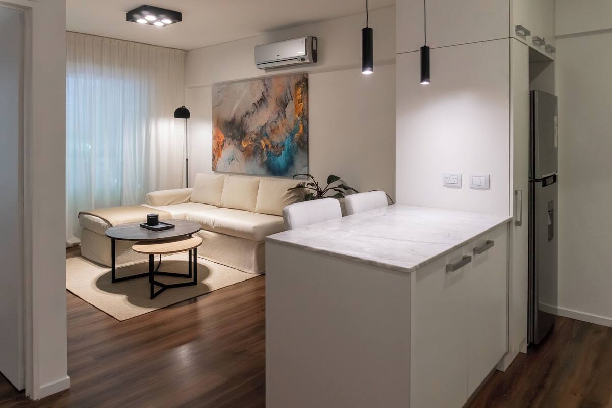 A modern living room with a sofa, coffee table, and a large abstract painting.